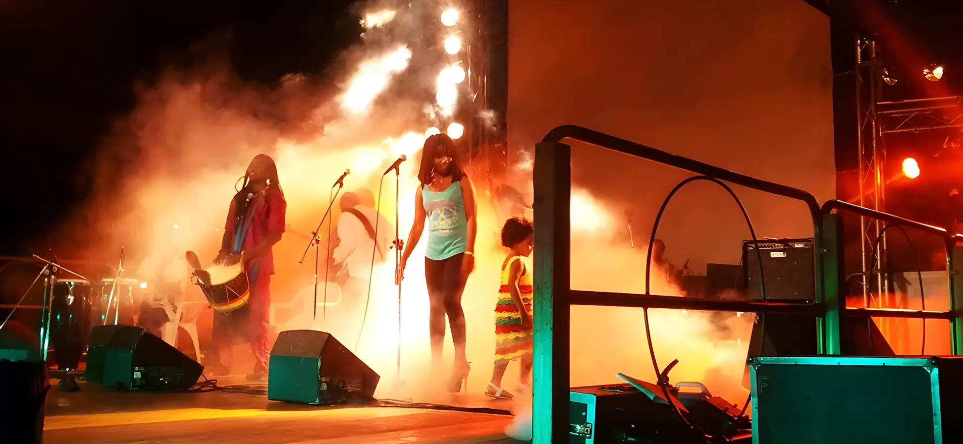 Concerto reggae con musicisti e cantanti su palco illuminato da fari professionali e effetti fumo, allestito da Disco Express