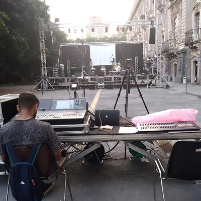 Tecnico audio luci alla regia durante preparazione palco per evento all’aperto in piazza