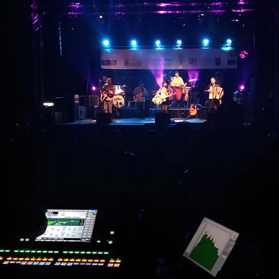 Concerto serale con band su palco illuminato e regia audio digitale in primo piano