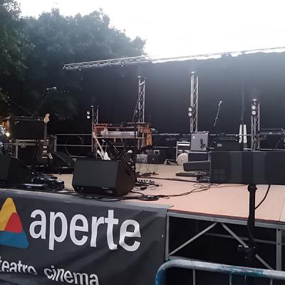 Palco pronto per concerto con strumenti musicali, impianti audio e struttura truss
