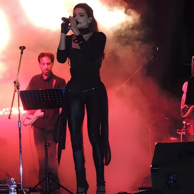 Band live con cantante sul palco tra effetti luce rossa e fumo scenico