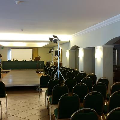 Sala conferenze allestita con palco, sedute, luci e proiettore per evento aziendale