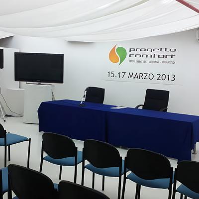 Sala conferenze minimal per evento Progetto Comfort con impianto audio e monitor