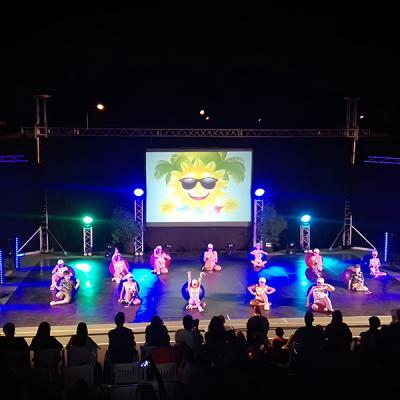 Spettacolo di danza serale con bambini in costume e sfondo di sole sorridente