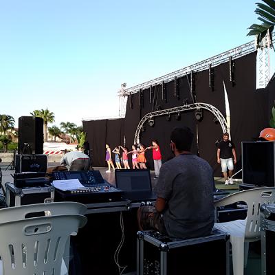 Tecnico audio gestisce prove di danza su palco all’aperto con gruppo di ballerine