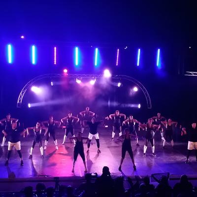 Gruppo di ballerini si esibisce su palco illuminato con luci a LED colorate durante uno spettacolo serale