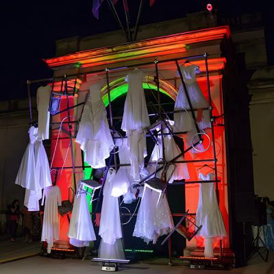 Installazione artistica di abiti bianchi sospesi con illuminazione scenografica notturna