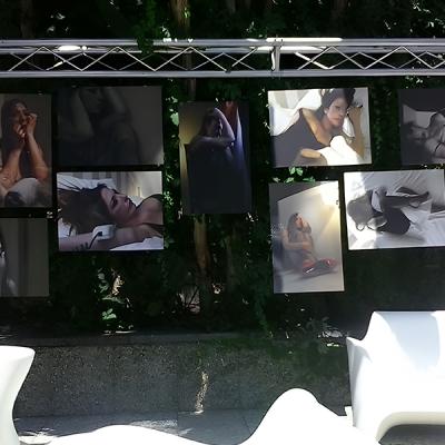 Mostra fotografica all’aperto con ritratti artistici in bianco e nero e a colori di una donna in pose intime ed espressive.