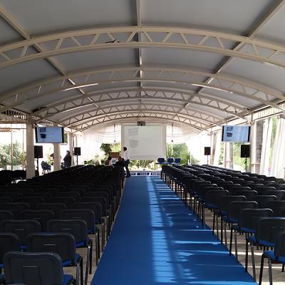 Allestimento per conferenza con sedie disposte e proiezione centrale in una struttura coperta.